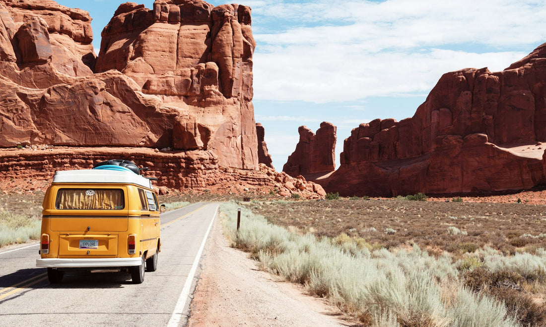 Yellow camper van driving through a desert canyon road