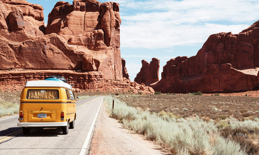 Yellow camper van driving through a desert canyon road
